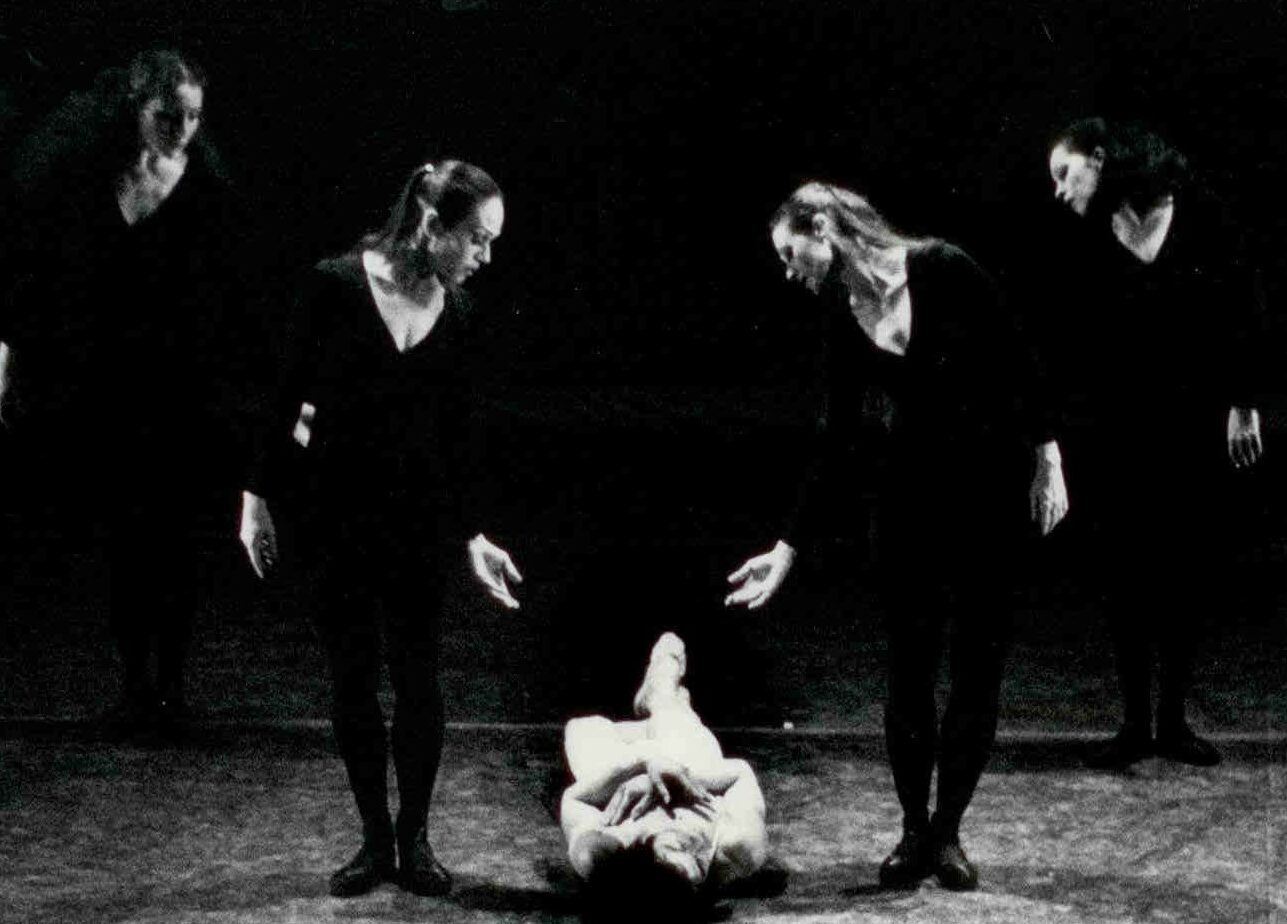 1970s: 4 dancers standing and making gesture to single dancer laying on the floor.