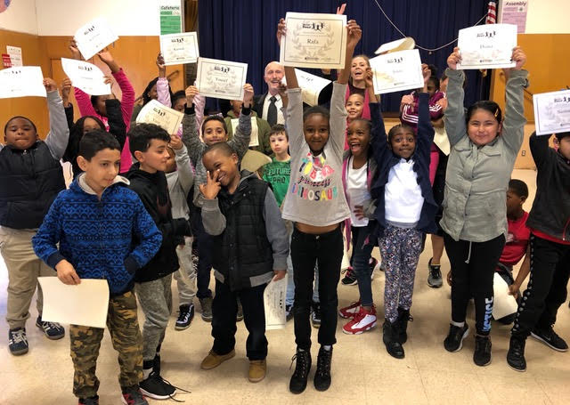 Students posing for camera, holding up certificates.