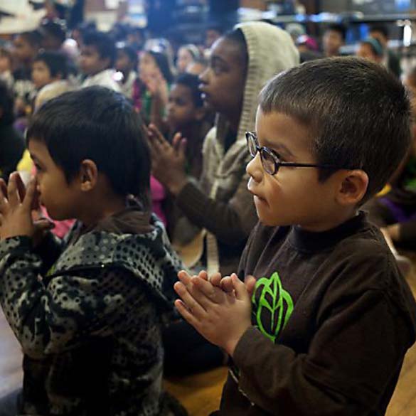 Young students watching and following clapping movements.