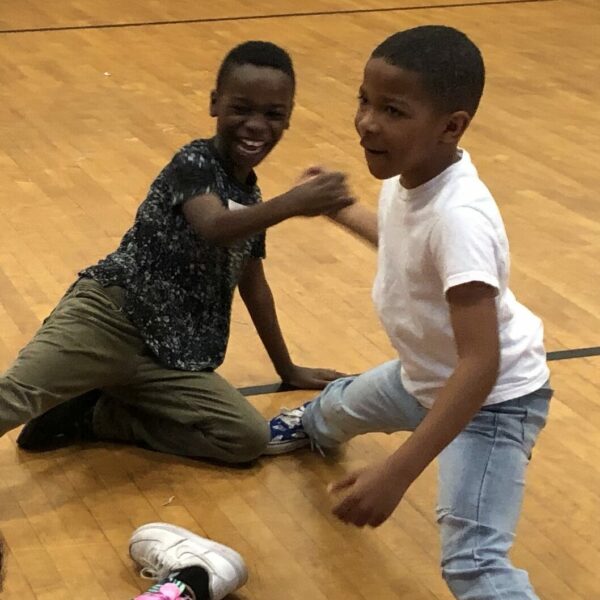 2 students playfully performing dance movement.