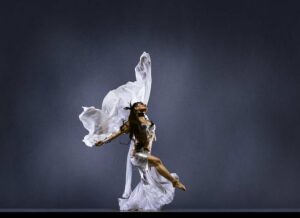 Dancer holding onto white, translucent cloth posing.