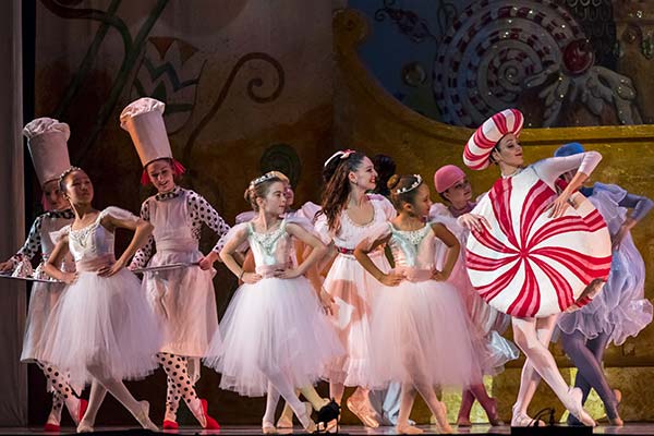 Nutcracker dancers dressed in pink looking to the right and posing legs crossed.