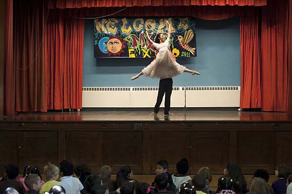 Dancers performing a duet for Nutcracker in front of student audiences.