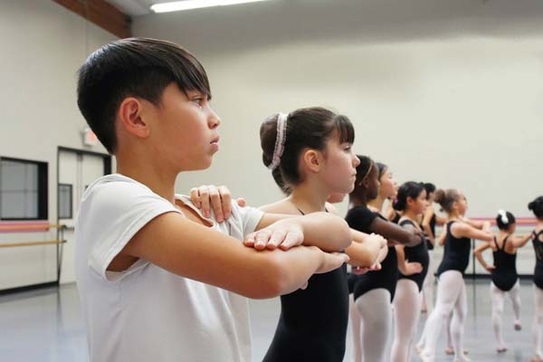 Young ballet students following movement instructions in the studio.