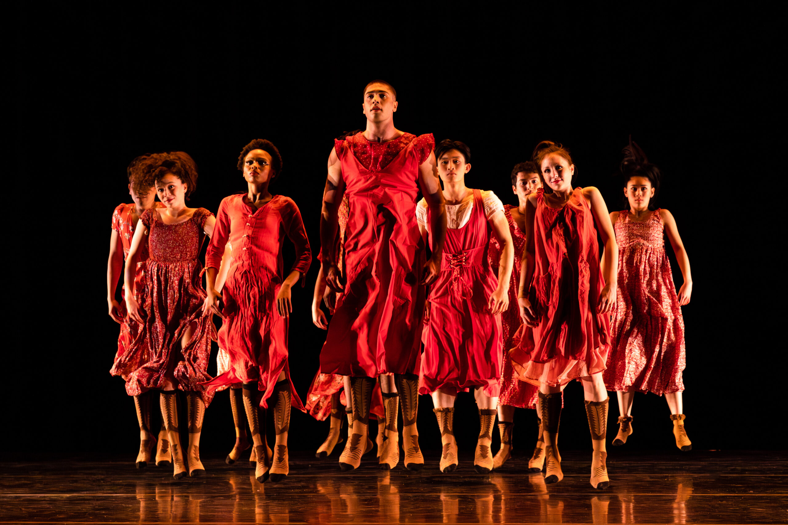 Full Company in Red costumes performing a hopping movement