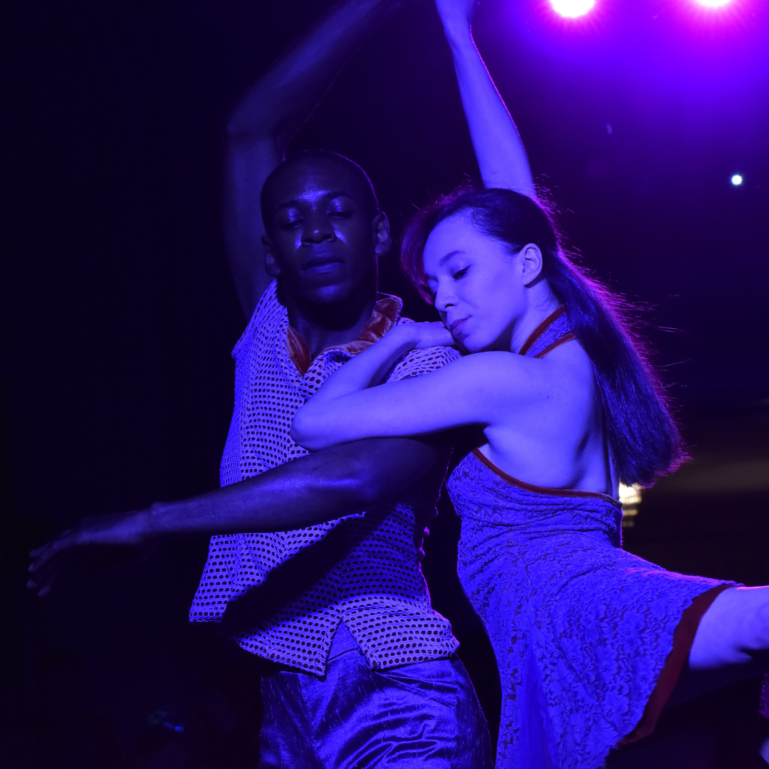 Dancers performing a duet with a purple hue light on them