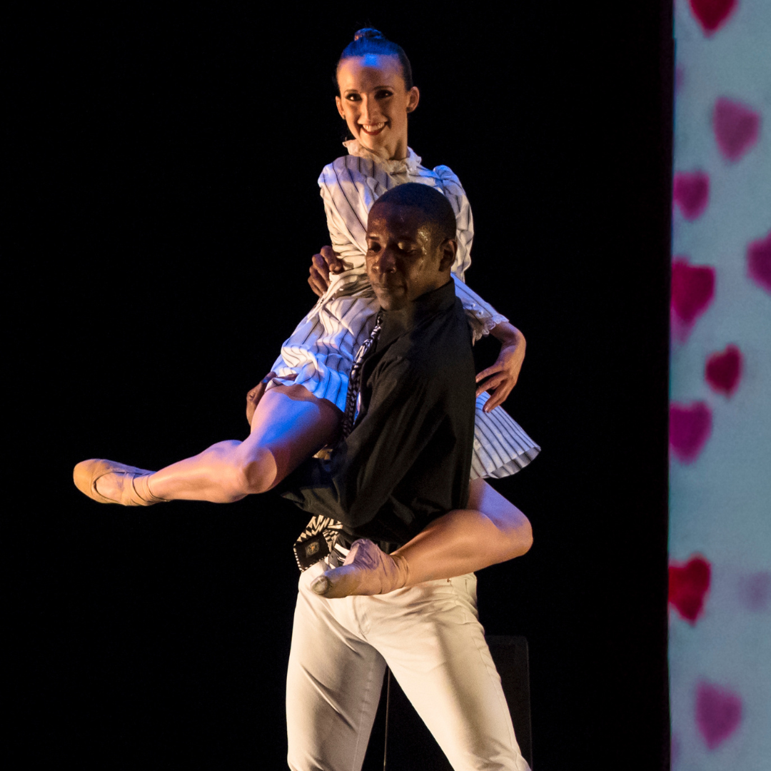 Dancer performs a lift in which top dancer wraps leg around and poses