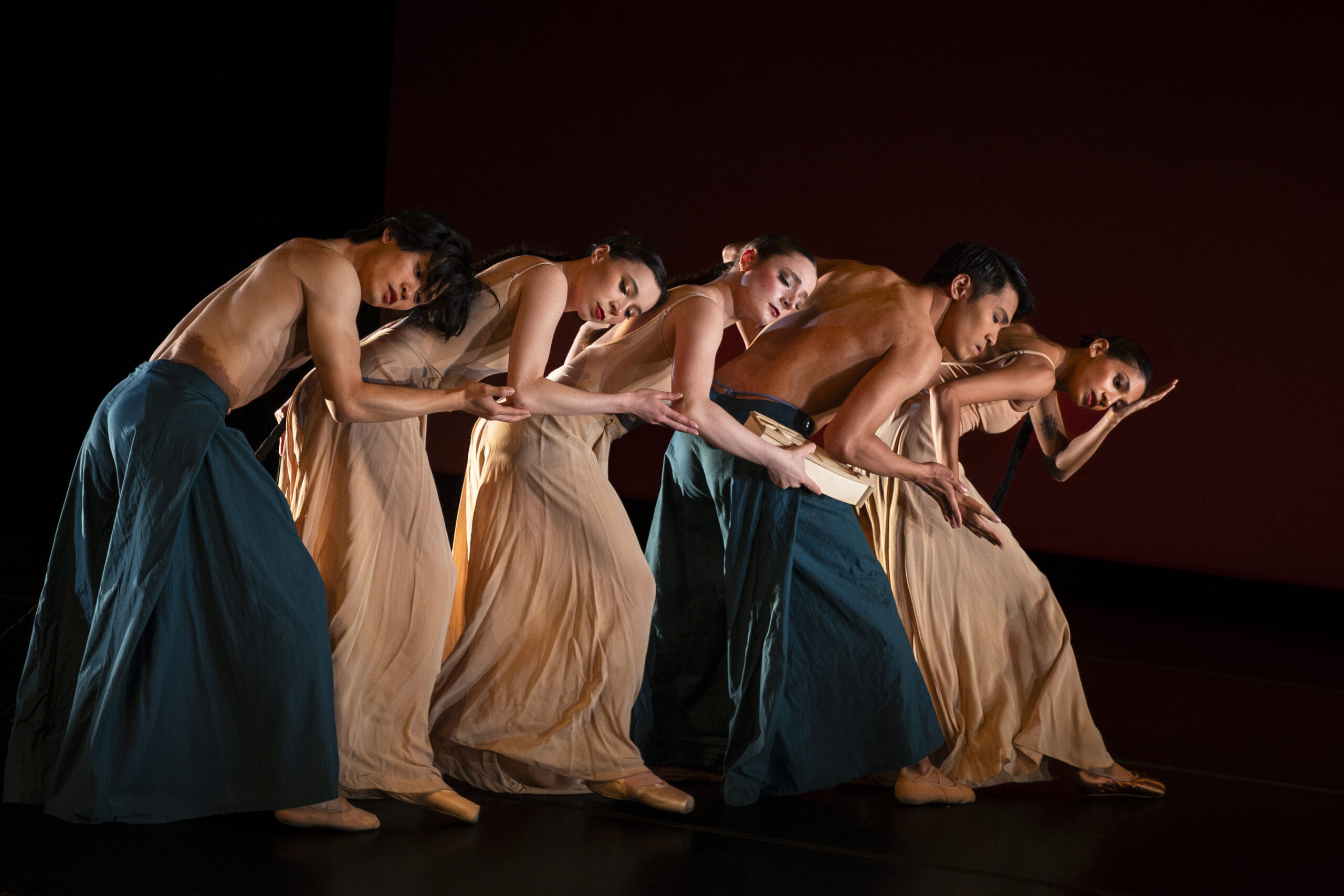 Dancers in a line facing the right leaned over one another.