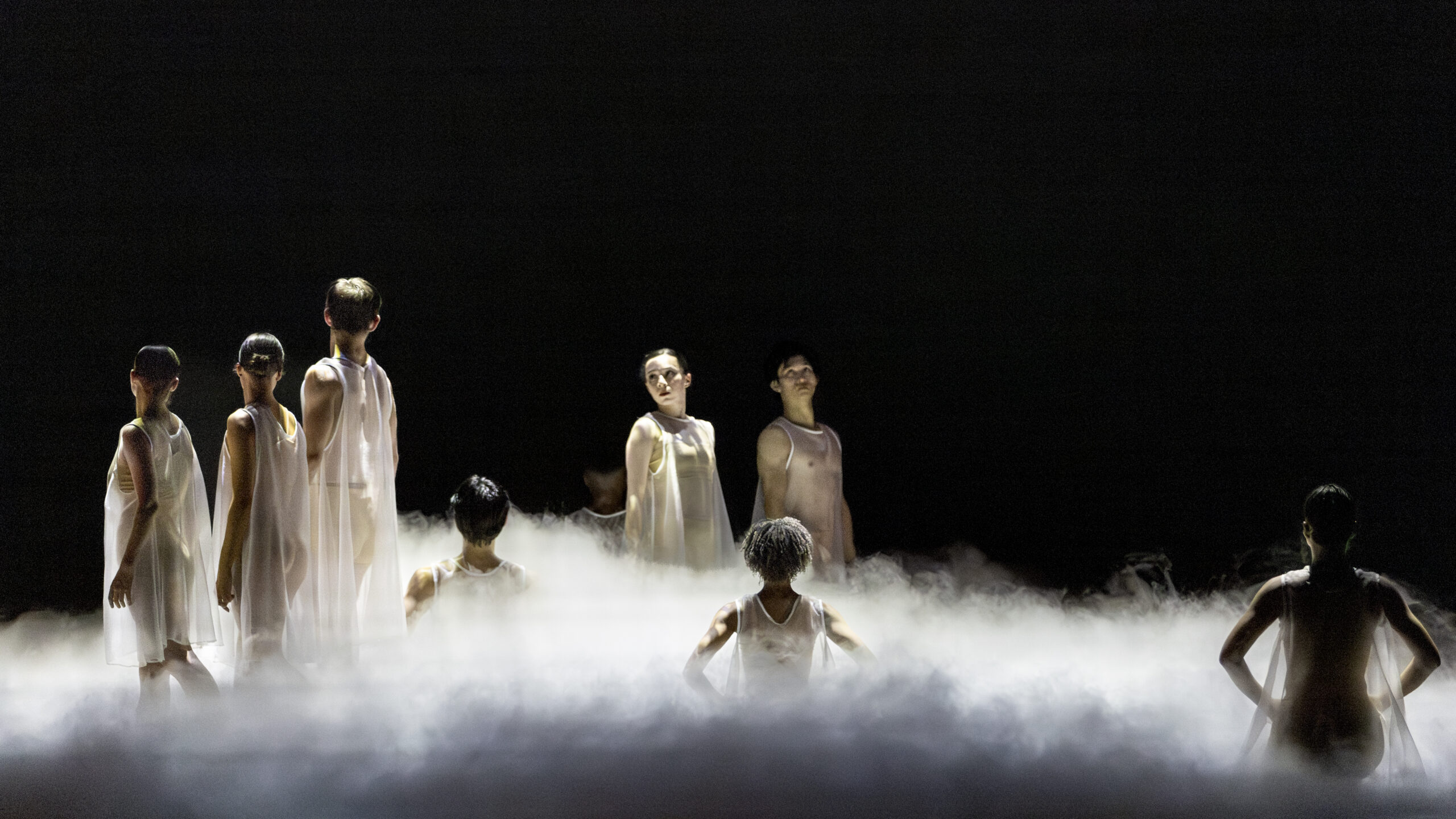 Dancers spread around the stage performing various poses connected by a long braid.